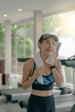 Woman wearing cap having rest while workout in gym. Wipe the sweat with a towel. fitness and sport concept.の写真素材