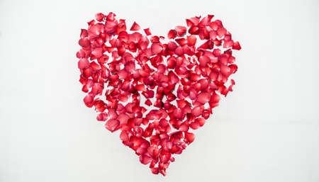 Honeymoon or wedding anniversary,  bed topped with rose in heart shape over white sheet.