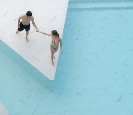 Couple walking to the pool made from white marble stone tile with blue ripped water.の写真素材