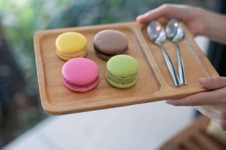 Colorful macaroons and spoon of coffee on a wooden tray.の写真素材