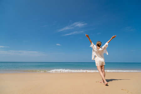 Happy young woman enjoying freedom with open hands on sea.
