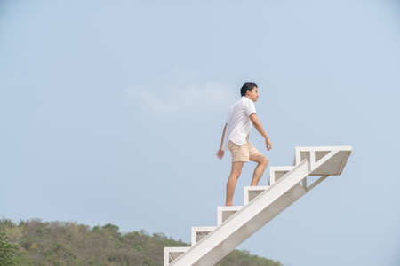 Man in white shirt walking up on the staircase.の写真素材