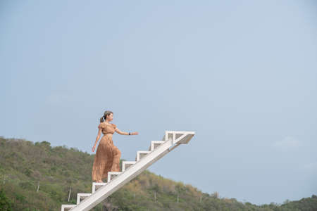 Woman in brown dress walking up on the staircase.の写真素材