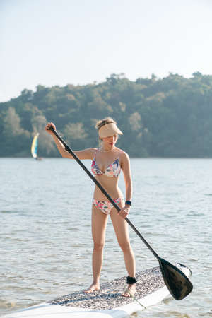 Woman wearing bikini on stand up paddle board or SUP in the sea. water sports , active lifestyle.