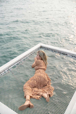 Woman lying on a pier with sea background, sit on the net by the sea.の写真素材