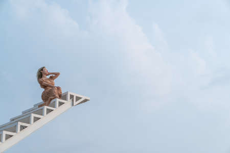 Woman in brown dress sitting on the staircase.の写真素材