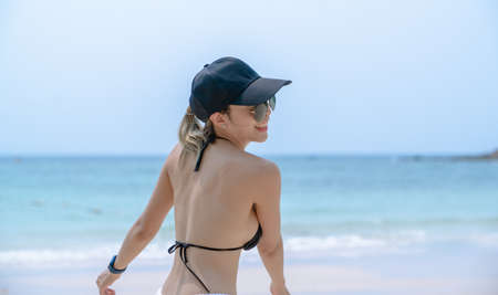 Woman in black bikini on tropical beach. Portrait woman in swimwear enjoying and posting on the beach.の写真素材