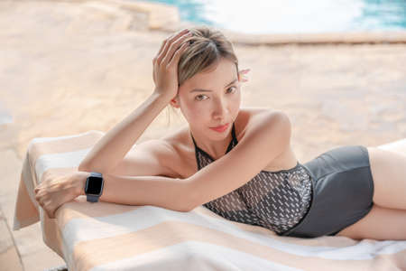 Asian woman sunbathing and relaxing on the sunbed at poolside.の写真素材