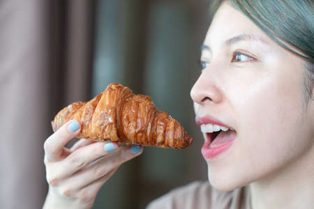 Woman eating baked crispy croissants.