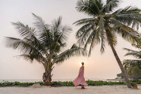 Woman in pink dress enjoying beautiful sunset on the Beach.の写真素材