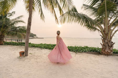 Woman in pink dress enjoying beautiful sunset on the Beach.