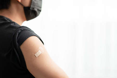Man wearing mask arm with bandage showing his arm after receiving vaccine.の写真素材