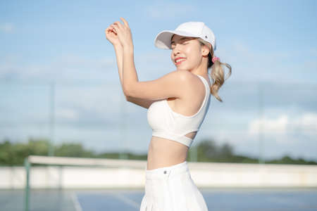 Woman tennis player in a white skirt resting on a tennis court.
