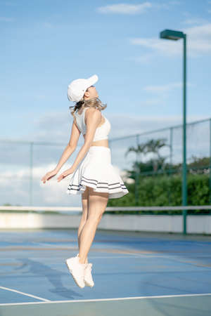 Woman tennis player in a white skirt resting on a tennis court.