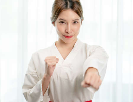 Portrait of woman in Taekwondo clothes show fighting pounch on white background .の写真素材