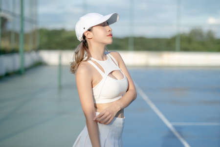 Woman tennis player in a white skirt resting on a tennis court.の写真素材