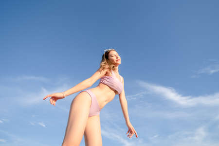 Portrait of woman in purple bikini swimwear with sky background. Summer vacation.の写真素材