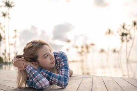 Woman wear one piece swimsuit laying near pool at beach, sunset moment.の写真素材