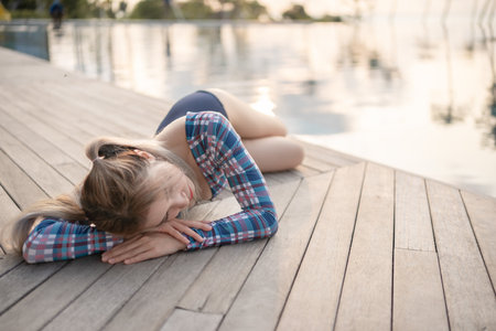 Woman wear one piece swimsuit laying near pool at beach, sunset moment.の写真素材