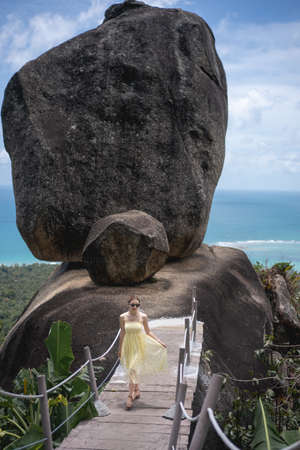Woman in yellow dress walking to overlap with ocean view background.