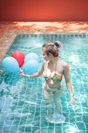 Woman in swimming pool having fun with balloons.