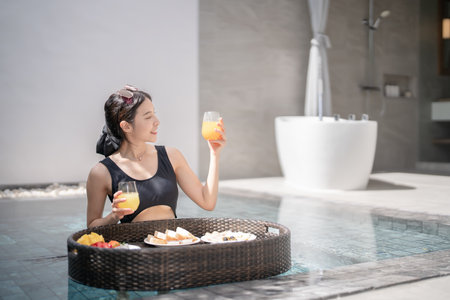 Woman relaxing and eating floating breakfast in the pool on luxury villa.の写真素材