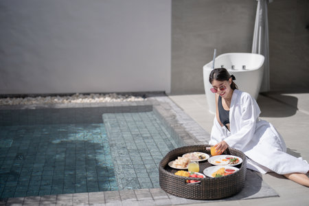Woman relaxing and eating floating breakfast in the pool on luxury villa.