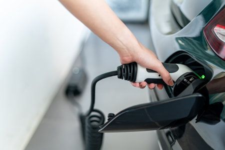Woman plugged cable charging an electric car at home.