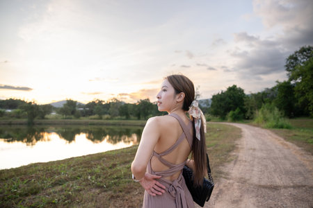 Young woman standing near lake during sunset,  beautiful nature.