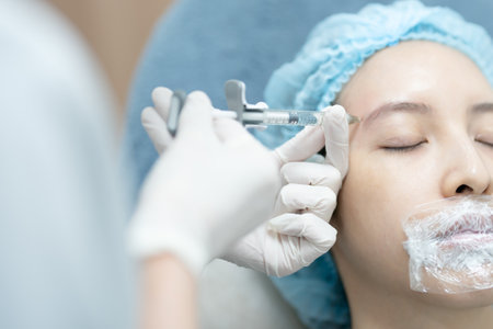 Plastic surgeon injection filler in temple of asian woman patient.