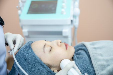 Beautician hand making ultrasound facial procedure by special equipment.