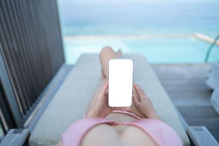 Hand with white blank mobile phone screen mockup with ocean background.の写真素材