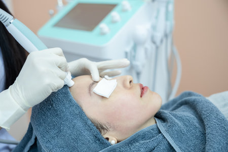Beautician hand making ultrasound facial procedure by special equipment.