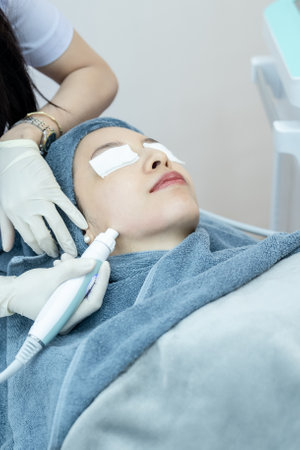 Beautician hand making ultrasound facial procedure by special equipment.