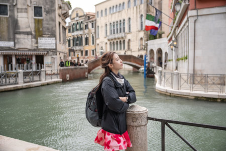 Woman stands near the canal on vintage corridor of Old architecture of Venice, Italy.の写真素材