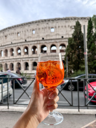 Colosseum (Colosseo) exterior with glass of cocktail in hand . Rome, Italy.の写真素材