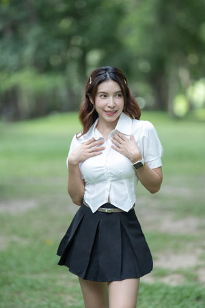 Student girl in Thai university uniform walk in the park outdoor.の写真素材