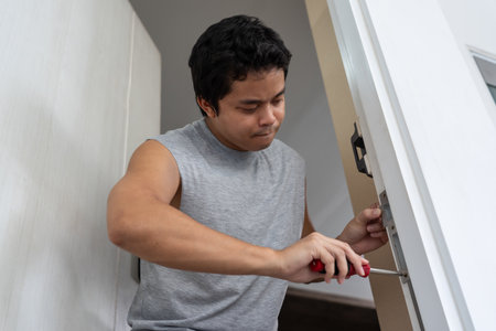 Man technician installs digital door lock on the wood door.の写真素材