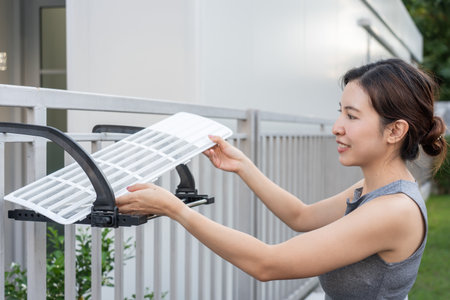 Woman Maintenance cleaning and replacing dirty air filter of air conditioning unit.の写真素材