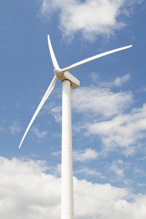 Wind turbine against a sky blue background with clouds の写真素材