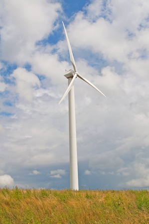 Wind turbine against a sky blue background with clouds の写真素材
