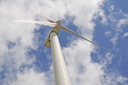 Wind turbine against a sky blue background with clouds の写真素材