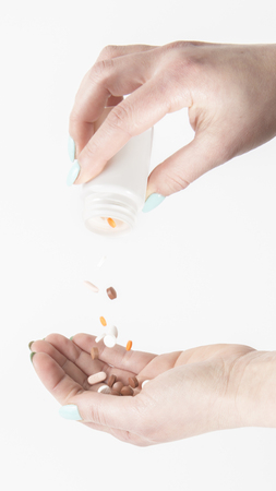 spilling tablets from white medication bottle into a human handの写真素材