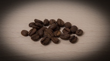 Black coffee seeds been closeup isolated on the wooden boardの写真素材