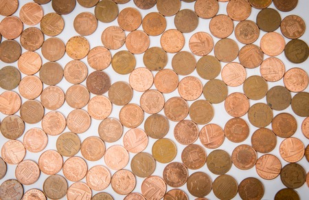 Many metal golden coins lying at the white backgroundの写真素材