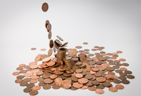 metal falling from the sky on the white background table isolated and hitting other coinの写真素材