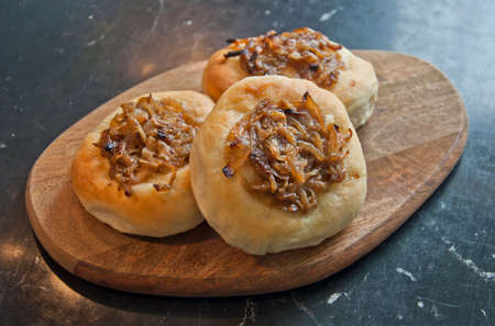 Bunch of tasty home made onion rolls on wooden plate.の写真素材