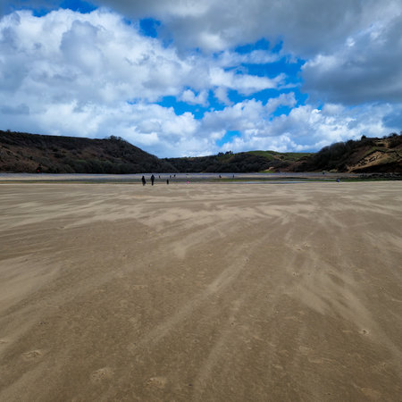 The three cliffs are visible in the background, with their sharp angles and rugged textures adding an element of drama to the scene. The calm, clear waters of the bay provide a perfect backdrop for surfing, swimming, or simply enjoying a peaceful day at the beach.の写真素材
