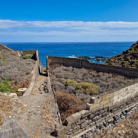 Embarking on a serene journey along the coastline of Puerto de la Cruz, the path leads towards the secluded beauty of Playa El RincÃ³n. With every step, the rhythmic sound of waves crashing against the shore accompanies the walker, while the salty breeze whispers tales of the vast ocean.の写真素材