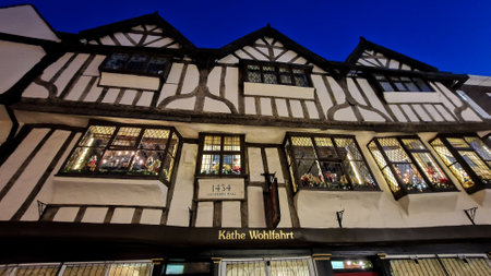 A beautifully preserved Tudor building in York, England,  illuminated by warm interior lights that cast a welcoming glow through its leaded windows. The timber-framed structure, known as Mulberry Hall, reflects the city's rich history.のeditorial素材